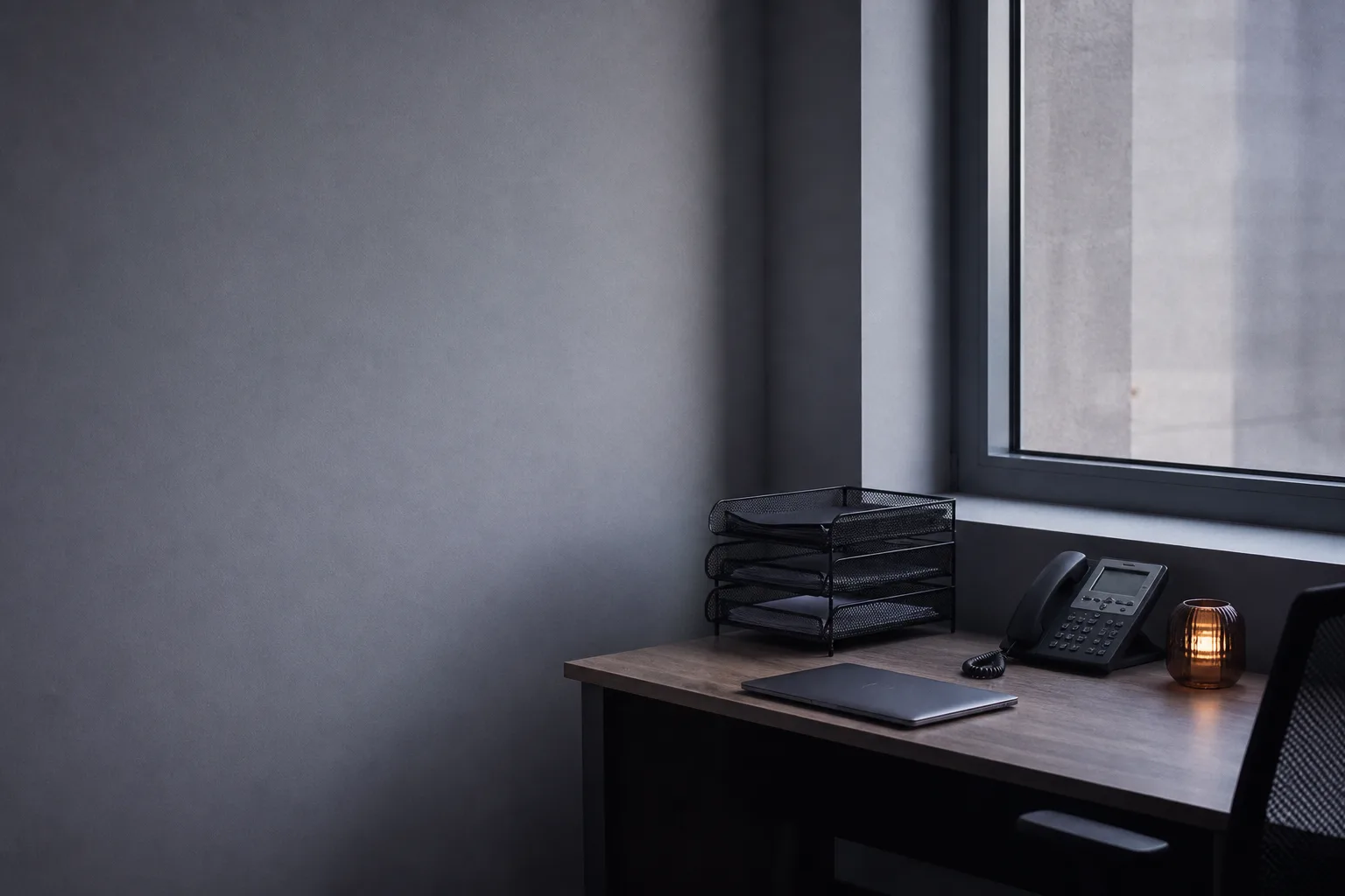A sales desk set up for email and SMS follow-up: paper trays, a closed laptop and a corded desk phone.